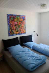 deux oreillers bleus sur un canapé avec un tableau sur le mur dans l'établissement Charming Cottage Close To The Beach, à Vester Sømarken