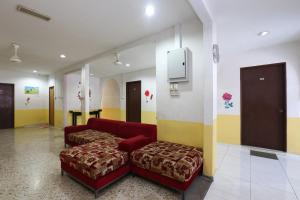 a waiting room with a red couch and a stool at OYO 89925 Innap Kota Bharu in Kota Bharu