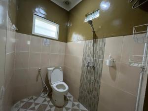 La salle de bains est pourvue d'une douche et de toilettes. dans l'établissement Omah Belimbing RedPartner near ABM Malang, à Blimbing