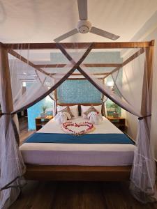 a bedroom with a canopy bed with a ceiling fan at Sri Palms in Kosgoda