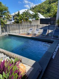 a swimming pool with lounge chairs next to a building at VILLA L HORIZON 4 appartements avec piscine in Petite Île