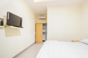 a bedroom with a bed and a flat screen tv at Omah Belimbing RedPartner near ABM Malang in Blimbing