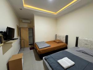 Cette petite chambre comprend deux lits et une télévision. dans l'établissement Omah Belimbing RedPartner near ABM Malang, à Blimbing