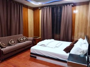 ein Bett und ein Sofa in einem Zimmer mit Vorhängen in der Unterkunft Pacific guest house in Skardu