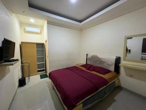 a bedroom with a bed and a flat screen tv at Omah Belimbing RedPartner near ABM Malang in Blimbing
