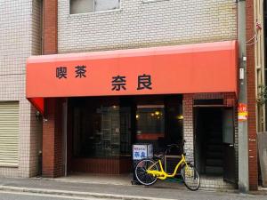 ein vor einem Gebäude parkendes gelbes Fahrrad in der Unterkunft ホリディパールホテル in Osaka