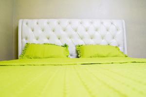 a bed with green sheets and two green pillows at The Vacation Homes Apartments in Kigali