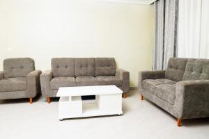 sala de estar con 2 sillas y mesa de centro en The Vacation Homes Apartments en Kigali