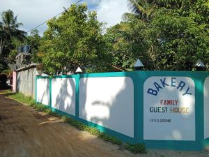 a sign for a family guest house next to a dirt road at Bakery Family Guest House in Mirissa