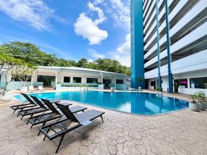 una piscina con tumbonas junto a un edificio en Puteri Front Beach Resort Studio Melaka 4pax/1park, en Kampong Pantai Dusun