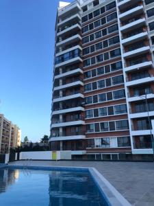 a tall building with a swimming pool in front of it at PALMVILLAGE MIKOCHENI in Dar es Salaam