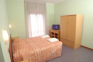 a bedroom with a bed and a cabinet and a television at Hotel Del Duca in Montedinove