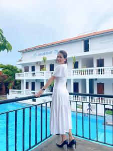 una donna con un vestito bianco in piedi accanto alla piscina di Caroline Resort a Vung Tau