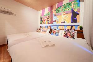 a bedroom with two beds and a painting on the wall at 板橋駅前店・ダイヤモンド・悠 in Tokyo