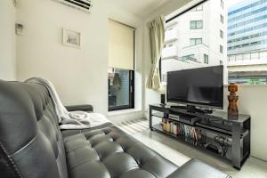 uma sala de estar com um sofá e uma televisão de ecrã plano em Pencil House - 10 mins walk to Shinjuku em Tóquio