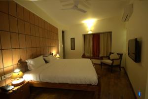 a bedroom with a large bed and a television at Nisargha Serviced Apartments in Bangalore