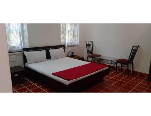- une chambre avec un lit, deux chaises et une table dans l'établissement Shubham Resorts, Solapur, à Solapur