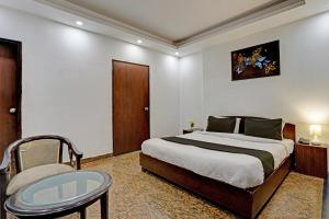 a bedroom with a bed and a chair and a table at Hotel VM Residency in New Delhi