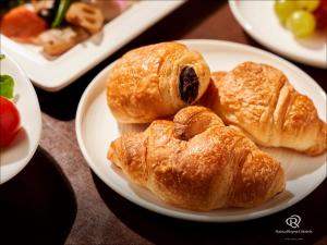 um prato de croissants e outros produtos de pastelaria numa mesa em Daiwa Roynet Hotel Takamatsu em Takamatsu