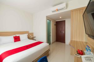 a hotel room with a bed and a television at RedDoorz at Homestay Lotus 2 Pangkal Pinang in Pangkalpinang