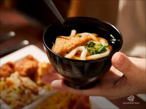 uma pessoa segurando um copo preto de comida em Daiwa Roynet Hotel Takamatsu em Takamatsu