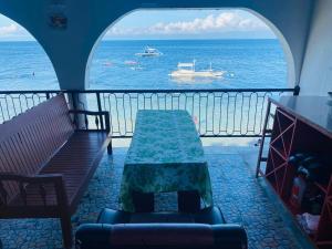 a balcony with a table and a boat in the water at SEASCAPE in Moalboal