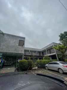 a car parked in a parking lot in front of a building at Come Moon Loft Hotel in Phrae