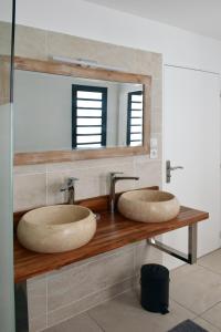 zwei Waschbecken auf einer hölzernen Theke im Bad in der Unterkunft Villa Paul Ermitage in La Saline-Les-Bains