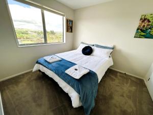 a bedroom with a bed with two towels on it at Cross Roads in Pokeno