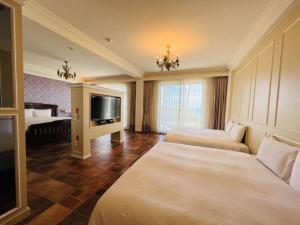 a hotel room with two beds and a flat screen tv at Kenting Moli Bay Seaview Resort Hotel in Fangshan