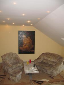 two chairs and a table in a room with a painting at Apartamentai Lampėdžiuose in Kaunas