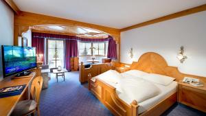 a hotel room with a bed and a television at Hotel Bergland in Lermoos