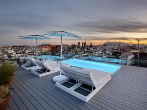 a row of lounge chairs with umbrellas on top of them at Yurbban Trafalgar Hotel in Barcelona