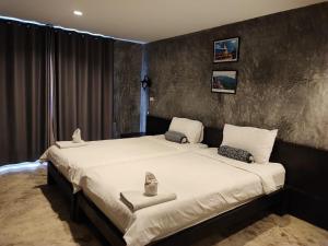 a bedroom with a large bed with white sheets at Come Moon Loft Hotel in Phrae