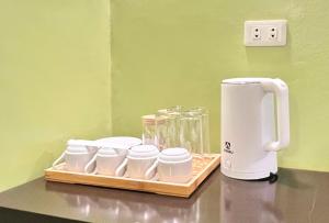 a coffee maker on a counter with a tray of cups at Damara Hotel at Ciudad Elmina in Dagupan