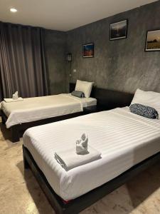 two beds with towels on them in a room at Come Moon Loft Hotel in Phrae