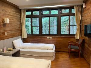 a room with two beds and a tv and a chair at Xitou Youth Activity Center in Lugu