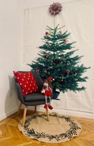 a christmas tree in a living room with a chair at Forst-Ház Apartman in Eger