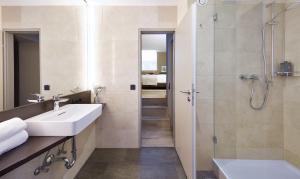 ein Bad mit einem Waschbecken und einer Dusche in der Unterkunft Living Hotel Nürnberg in Nürnberg