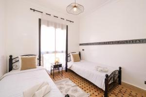 um quarto com duas camas e uma janela em Appartement aux portes de la palmeraie em Marraquexe