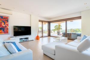 sala de estar con muebles blancos y TV de pantalla plana en Finca Es Niu, en Santa Eugènia