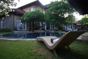 una sedia di vimini seduta sull'erba accanto a una piscina di Guildwood Villa Bali a Sanur