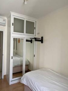 ein weißes Schlafzimmer mit einem Bett und einem Spiegel in der Unterkunft 2 bedroom next to Mall Central Park & Neo Soho (Medit 1) in Jakarta