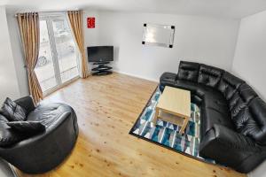a living room with a leather couch and a table at Thistle Apartments - King's Apartment in Aberdeen