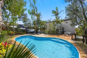 a swimming pool in front of a house with trees at Kings View in Peregian Beach