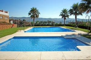 una piscina en un patio con palmeras en Apartamento Sietecolores Sea View, en Rincón de la Victoria