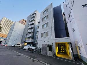 札幌市にある3-3札幌駅徒歩8分　美室【サービスアパートメントSAPPORO札幌駅西】エアコン完備の横に車を停めた路上の建物