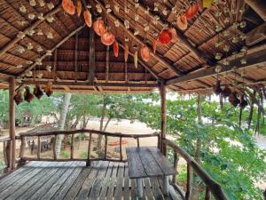 ジュム島にあるSunset Beach Bungalow Koh Puの茅葺き屋根の下にベンチのある木製のデッキ +18枚の写真