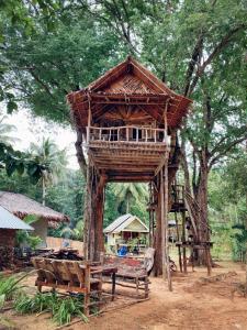 a tree house with a bench and a table at Sunset Beach Bungalow Koh Pu in Ko Jum