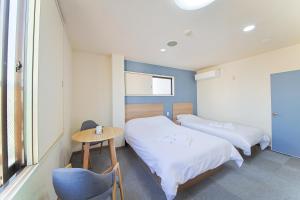 2 Betten in einem Zimmer mit einem Tisch und einem Stuhl in der Unterkunft ホテルよしや in Osaka